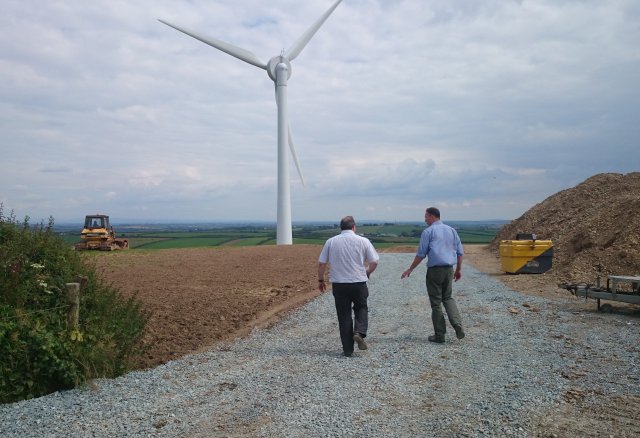 Two people walking in front of wind turbine